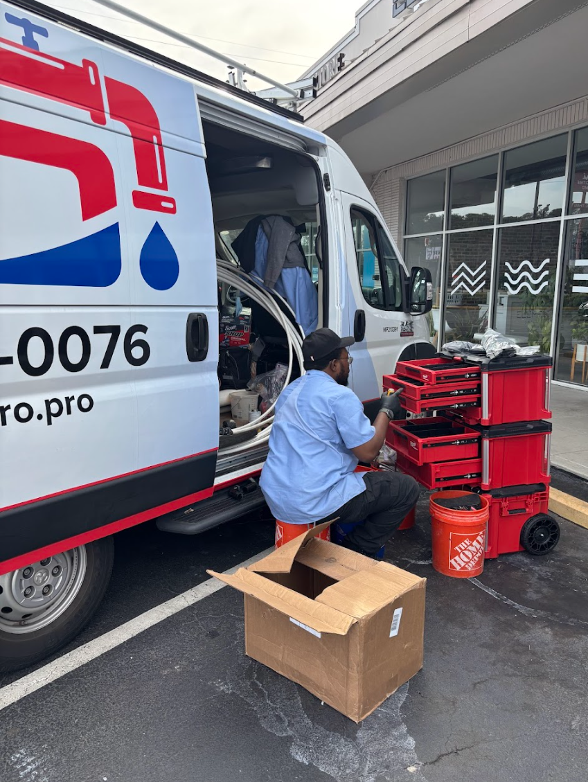 PlumbingPro North Atlanta — technician loading red Milwaukee tool carts into the side of a branded PlumbingPro van before a service call